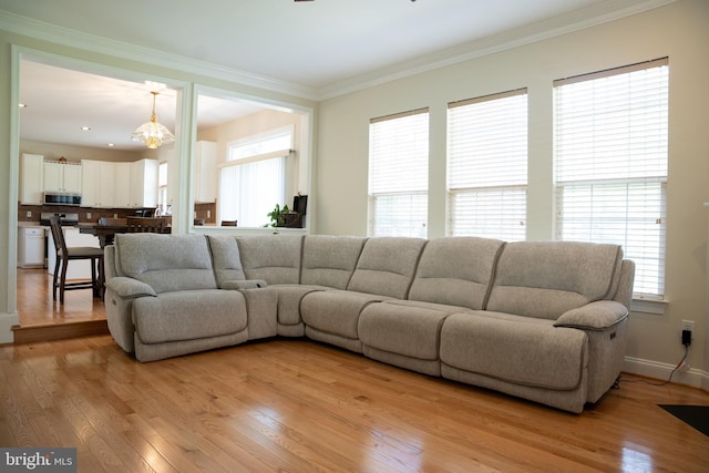 living room with light wood-type flooring, baseboards, and crown molding