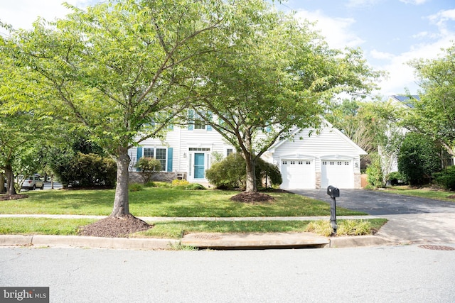 obstructed view of property featuring a garage, driveway, and a front lawn