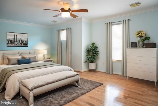 bedroom with visible vents, ornamental molding, a ceiling fan, light wood finished floors, and baseboards