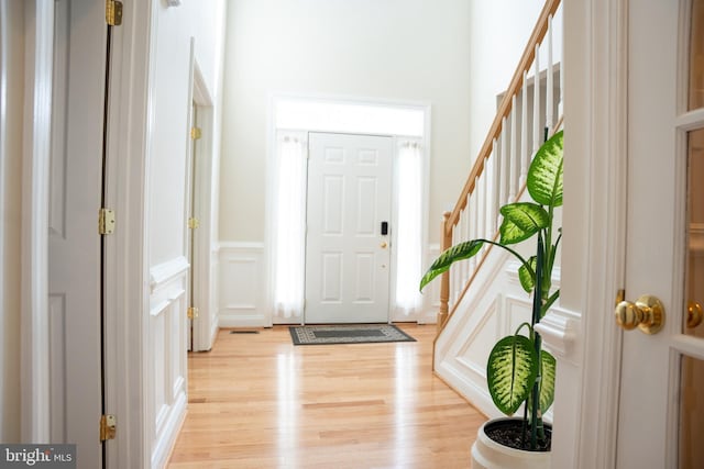 entryway with stairway, light wood-style flooring, and a decorative wall