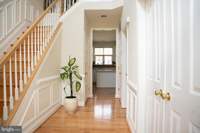 staircase featuring a decorative wall, wood finished floors, and a wainscoted wall