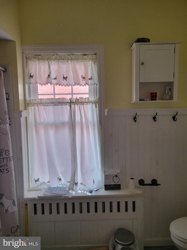 bathroom featuring radiator, wainscoting, and toilet