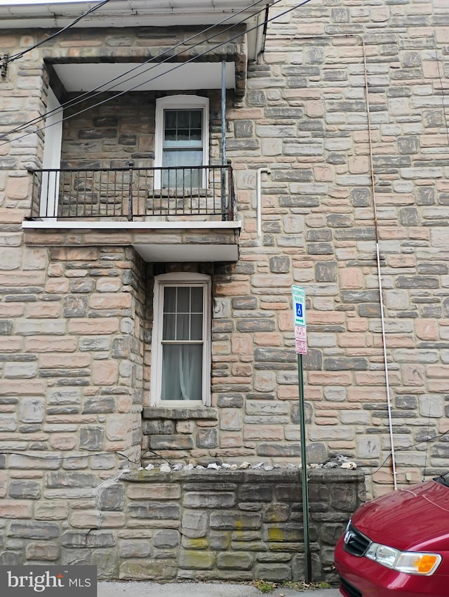 view of side of property featuring stone siding and a balcony