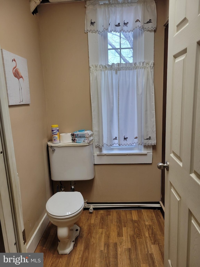 bathroom with toilet, baseboards, and wood finished floors