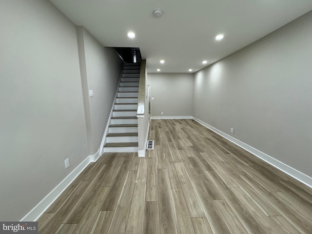 below grade area featuring stairs, wood finished floors, visible vents, and baseboards