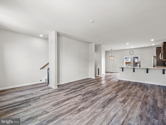 unfurnished living room with recessed lighting, dark wood finished floors, stairway, and baseboards