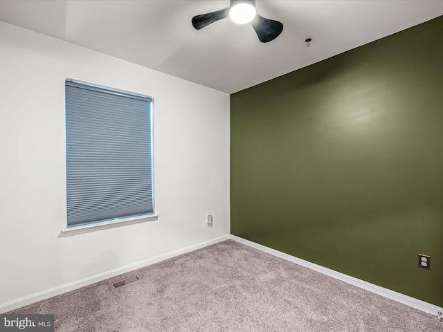 carpeted empty room with baseboards, visible vents, and a ceiling fan