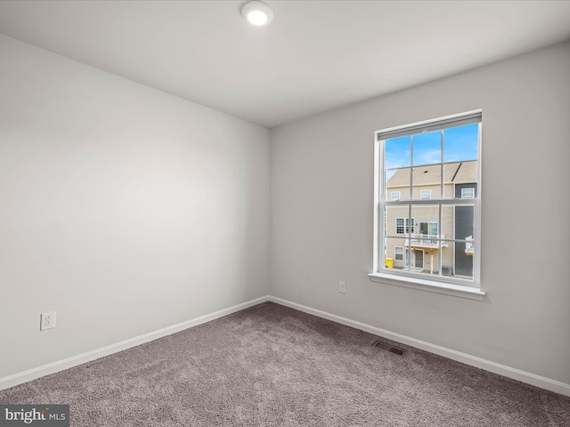 spare room with carpet, visible vents, and baseboards