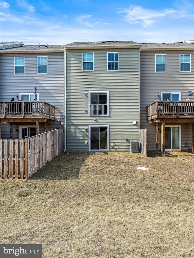 rear view of house with fence, cooling unit, and a yard