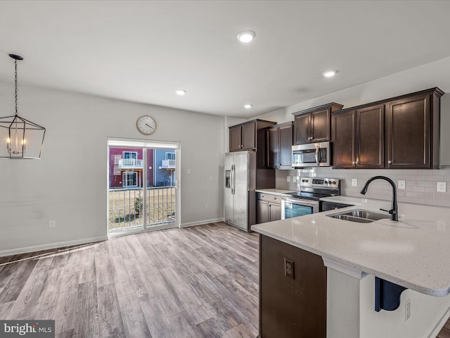 kitchen featuring light stone counters, stainless steel appliances, decorative backsplash, a sink, and dark brown cabinetry