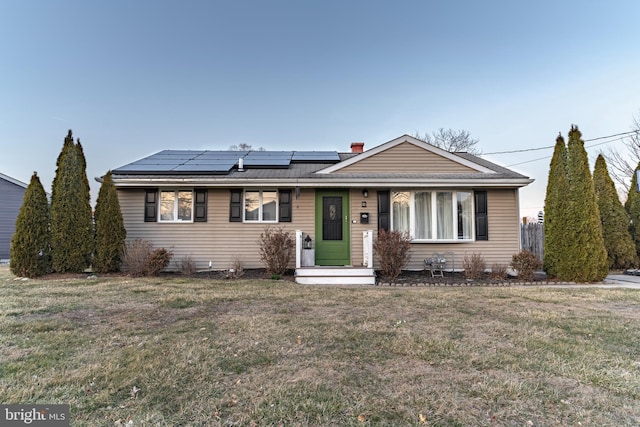 view of front of house featuring a front lawn and roof mounted solar panels