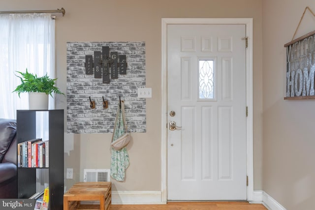 foyer featuring plenty of natural light, visible vents, baseboards, and wood finished floors