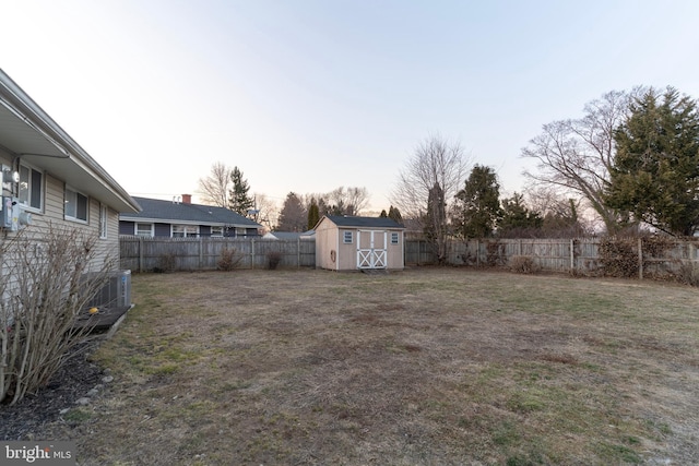 view of yard with central AC unit, a shed, an outdoor structure, and a fenced backyard