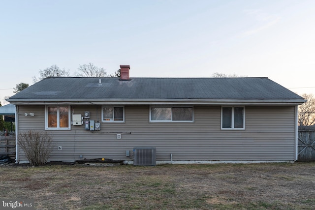 back of property with fence, a yard, a chimney, and central AC unit