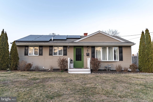 view of front facade featuring solar panels and a front lawn