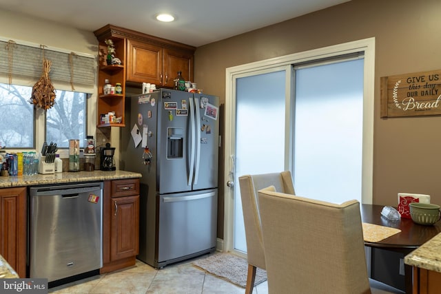 kitchen with open shelves, light tile patterned floors, appliances with stainless steel finishes, brown cabinetry, and light stone countertops