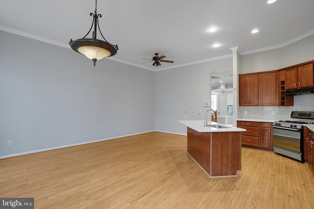 kitchen featuring tasteful backsplash, gas range, light countertops, light wood-style flooring, and a sink