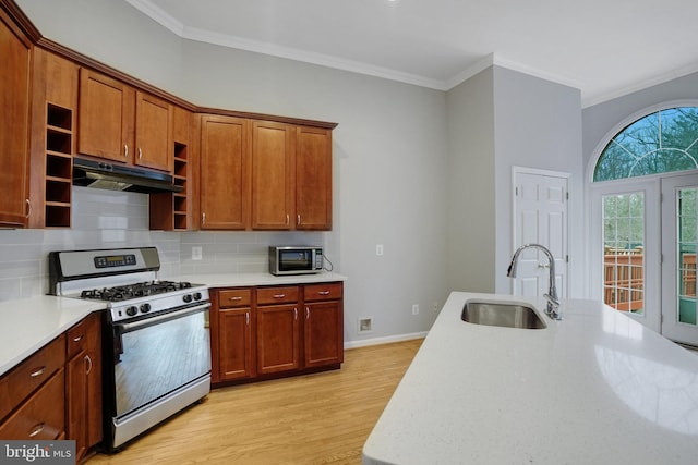 kitchen featuring under cabinet range hood, open shelves, a sink, stainless steel appliances, and light countertops