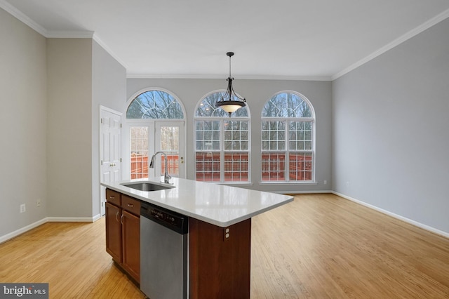 kitchen with pendant lighting, light wood-style flooring, a sink, stainless steel dishwasher, and light countertops