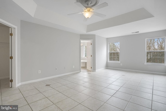 unfurnished bedroom with a tray ceiling, light tile patterned flooring, a ceiling fan, and baseboards