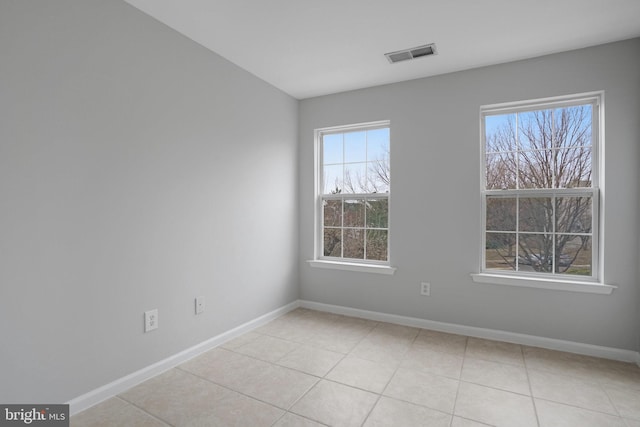 empty room with light tile patterned floors, visible vents, and baseboards