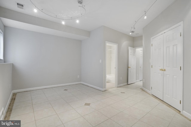 unfurnished bedroom with light tile patterned floors, baseboards, visible vents, ensuite bath, and a closet
