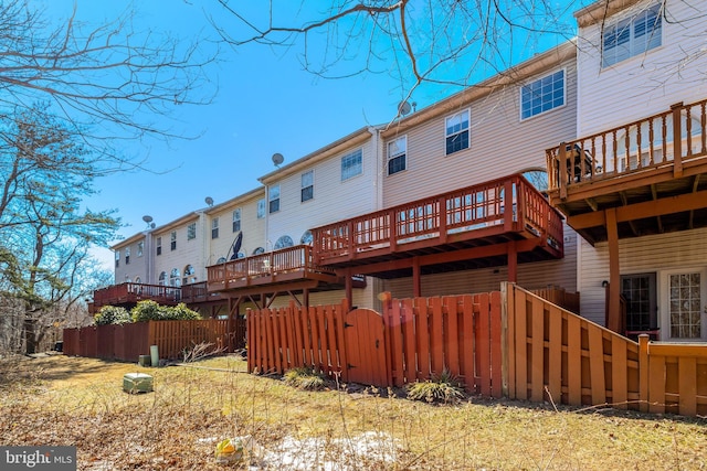 rear view of house with fence and a deck