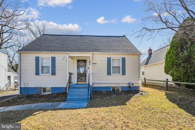 bungalow-style home featuring roof with shingles, a front yard, and fence