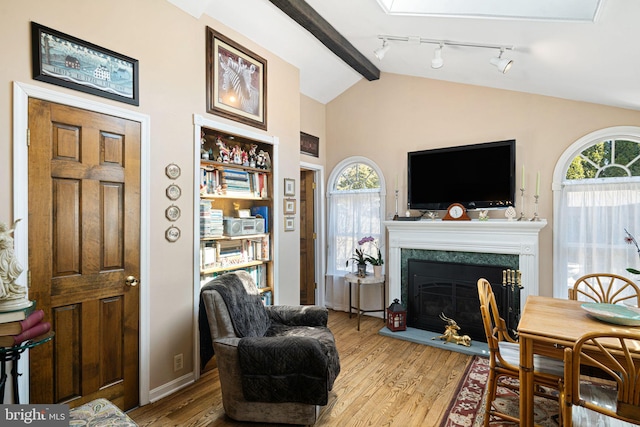 living area featuring a wealth of natural light, vaulted ceiling with beams, and wood finished floors