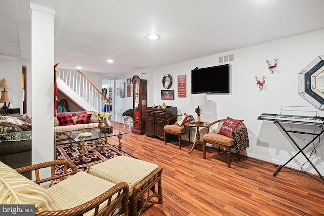 living room featuring arched walkways, recessed lighting, visible vents, light wood-type flooring, and stairs