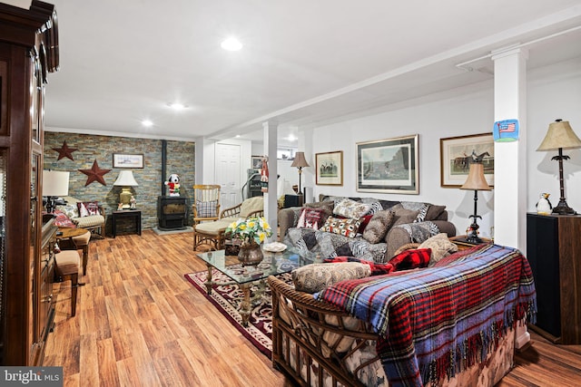 living room featuring light wood-style floors, recessed lighting, a wood stove, and ornate columns