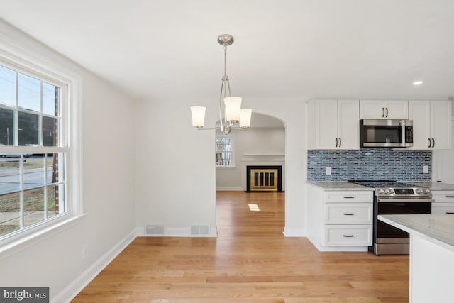 kitchen featuring light wood finished floors, stainless steel appliances, tasteful backsplash, visible vents, and white cabinetry