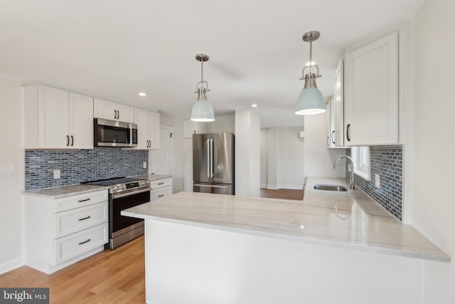 kitchen featuring a peninsula, appliances with stainless steel finishes, white cabinets, and a sink