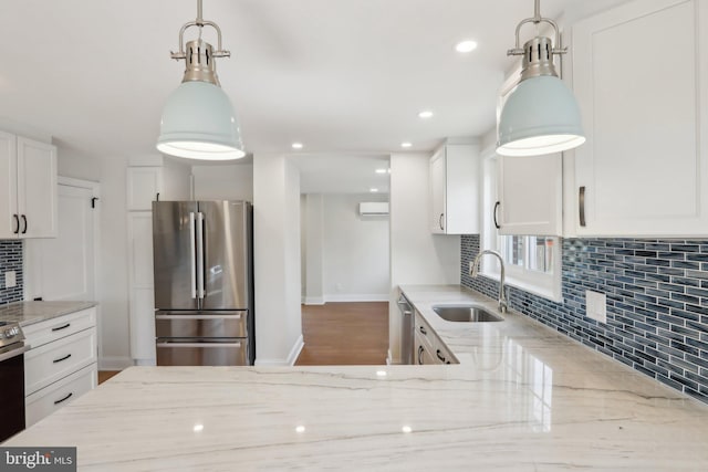 kitchen featuring appliances with stainless steel finishes, a sink, white cabinetry, and light stone countertops