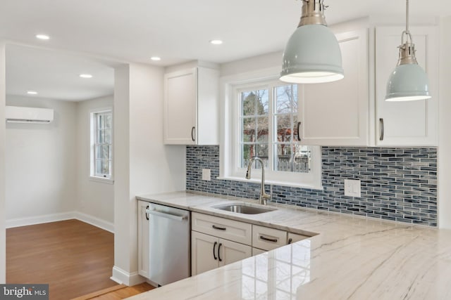 kitchen featuring plenty of natural light, dishwasher, light stone counters, a wall mounted air conditioner, and a sink