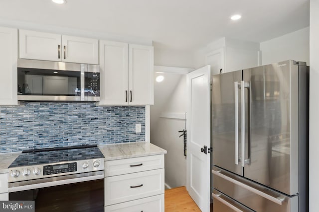 kitchen with light stone counters, recessed lighting, stainless steel appliances, white cabinetry, and decorative backsplash