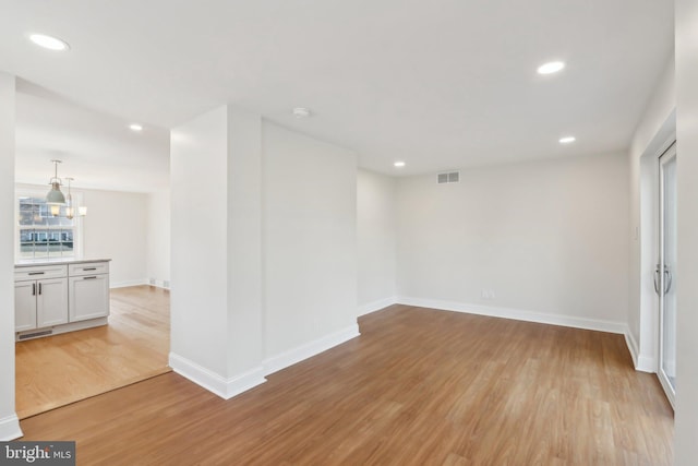 unfurnished room with a chandelier, light wood-style flooring, recessed lighting, visible vents, and baseboards