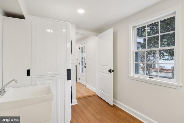 hallway with light wood-style floors, a healthy amount of sunlight, a sink, and baseboards