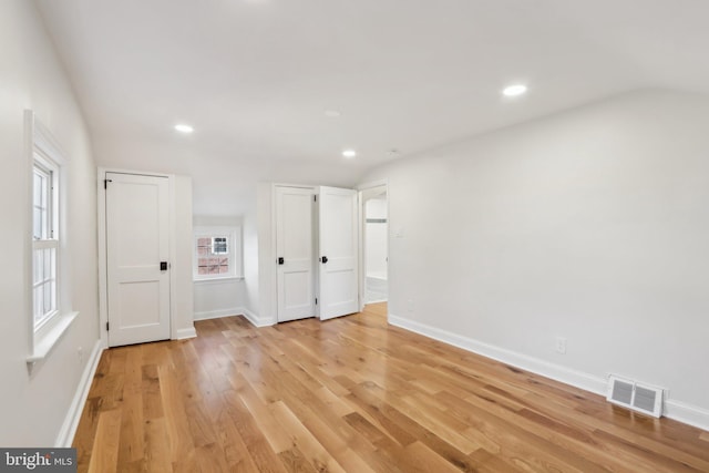 empty room with visible vents, light wood-style flooring, and baseboards