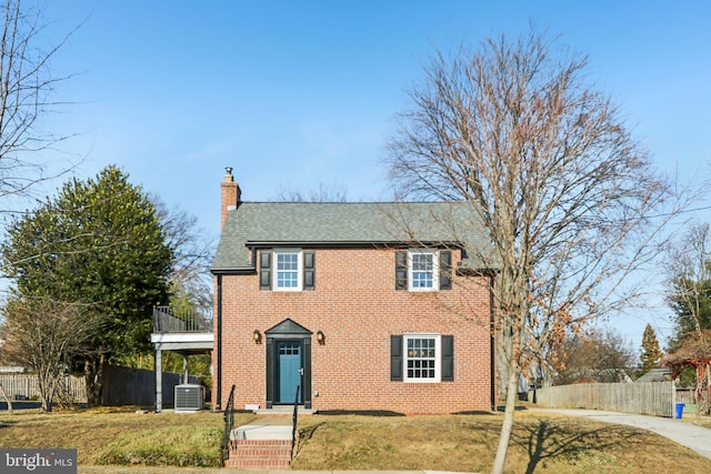 view of front of house with a chimney, fence, cooling unit, and brick siding