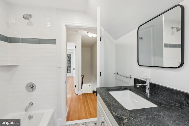 full bath featuring shower / bathtub combination, vaulted ceiling, wood finished floors, and vanity