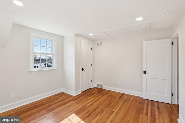 unfurnished room featuring attic access, baseboards, visible vents, and light wood finished floors