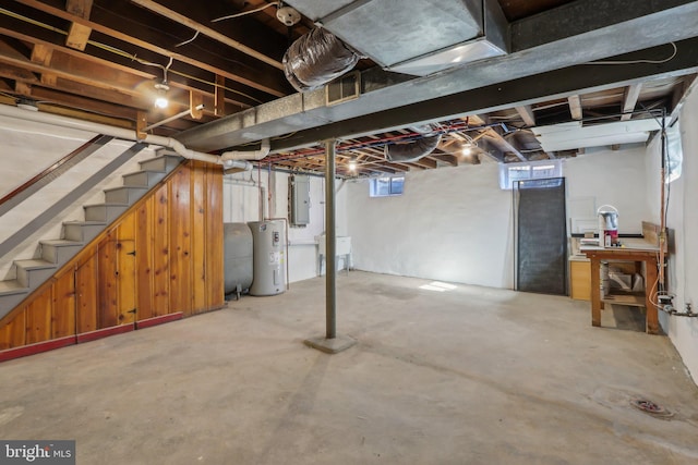 below grade area featuring electric panel, heating fuel, stairs, water heater, and a sink