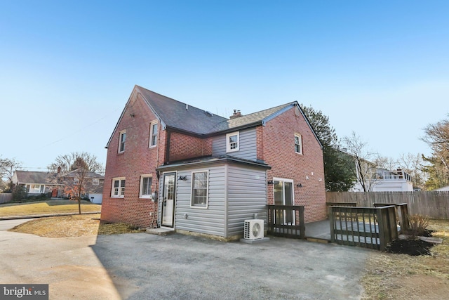 exterior space featuring ac unit, brick siding, a chimney, fence, and a deck