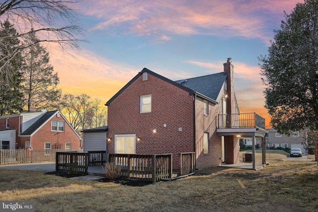 rear view of property featuring a chimney, central AC unit, a lawn, and brick siding