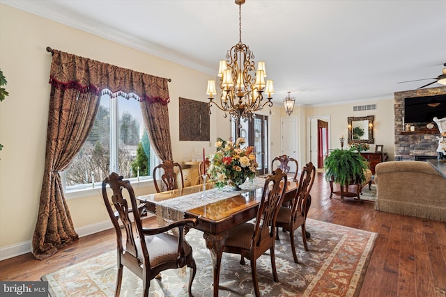 dining room with ceiling fan with notable chandelier, baseboards, hardwood / wood-style flooring, and crown molding