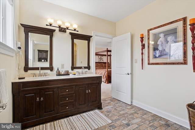 full bathroom with double vanity, brick floor, baseboards, and a sink