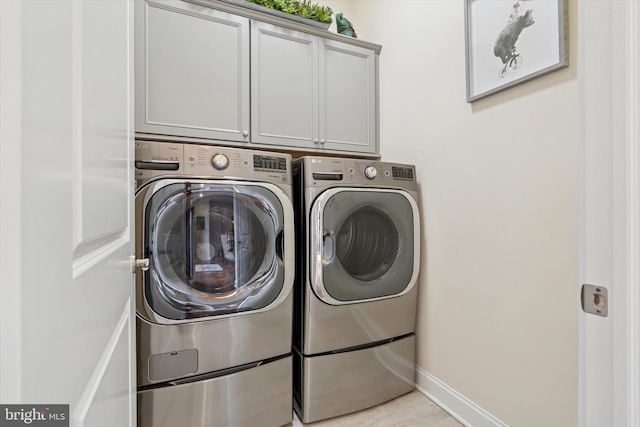 clothes washing area featuring cabinet space, baseboards, and separate washer and dryer