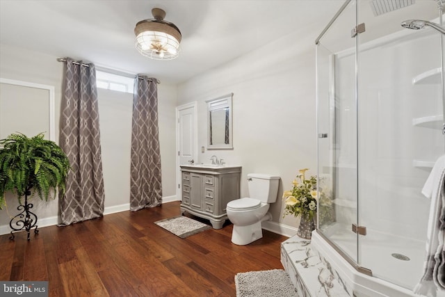 full bathroom with baseboards, toilet, wood finished floors, vanity, and a shower stall