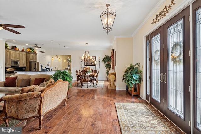 foyer with baseboards, hardwood / wood-style flooring, ornamental molding, french doors, and ceiling fan with notable chandelier